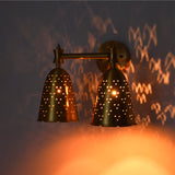 Angled illuminated double bell wall sconce creating decorative dotted light patterns and warm ambient glow.