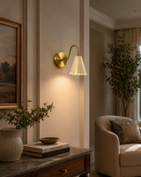 Luna Scalloped Cone Wall Sconce installed in a modern hallway, providing warm ambient lighting with a handcrafted white scalloped cone shade and solid brass curved arm.