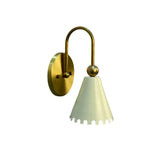 Front angled view of the Luna Scalloped Cone Wall Sconce featuring a handcrafted white scalloped metal shade, decorative brass sphere, curved solid brass arm, and round wall canopy.