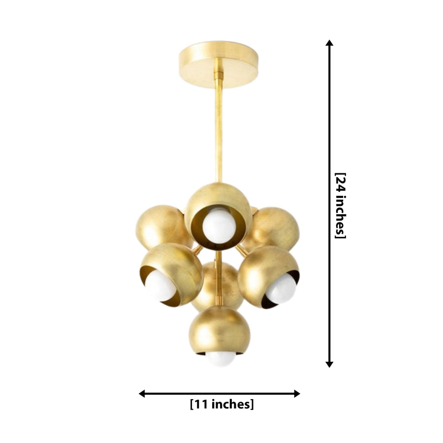 Lyon 7 light sculptural brass chandelier centered above a modern wood dining table with upholstered chairs.