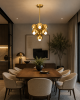 Lyon 7 light sculptural brass chandelier centered above a modern wood dining table with upholstered chairs.