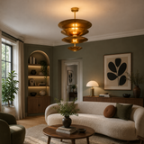 Mallorca 8 light brass-tone tiered disc chandelier installed in a warm contemporary living room above a seating area.