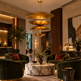 Mallorca 8 light brass-tone tiered disc chandelier displayed above a luxury lounge seating area with marble and velvet furnishings.