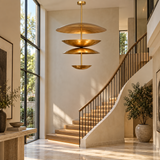 Mallorca 8 light sculptural brass-tone chandelier displayed in a modern staircase foyer with tall windows and natural daylight.