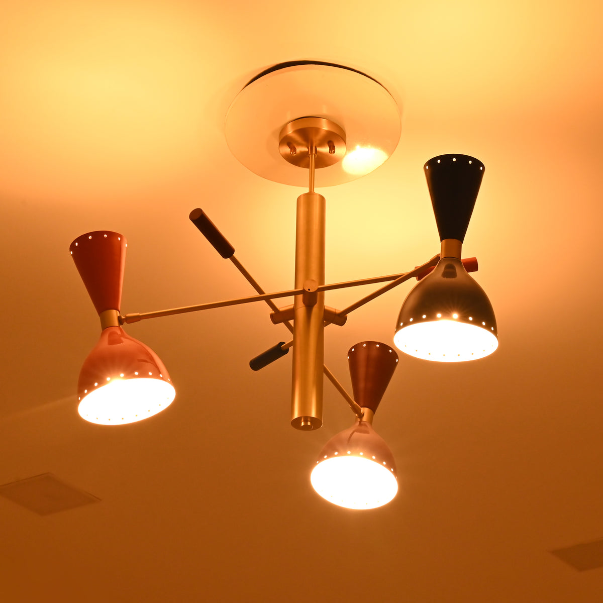 Manhattan sculptural brass-tone Sputnik chandelier with orange, blue, and brown shades illuminated in warm ambient evening lighting.