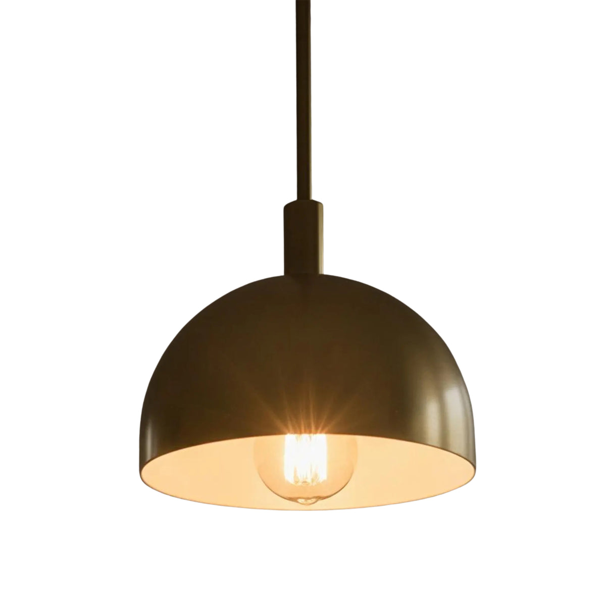Close-up of Marlow brass dome pendant light illuminated with warm downward lighting and exposed bulb.
