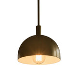 Close-up of Marlow brass dome pendant light illuminated with warm downward lighting and exposed bulb.