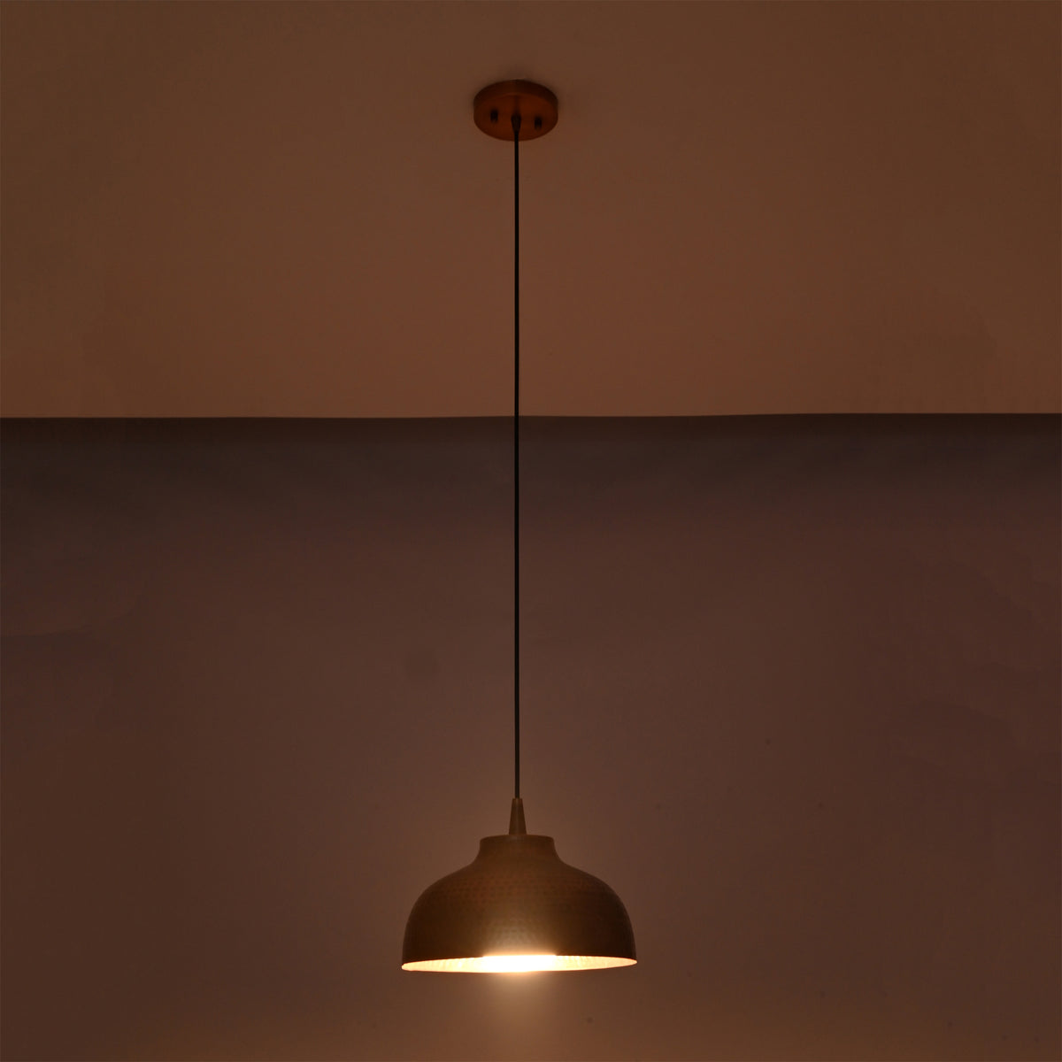 Marlow hammered copper dome pendant light emitting focused warm downward light from its handcrafted hammered copper shade.