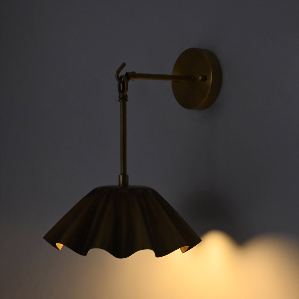 Side illuminated view of the Marlow Modern Pleated Flower Wall Sconce highlighting the sculptural pleated metal shade and soft ambient lighting effect from the frosted opal glass globe.