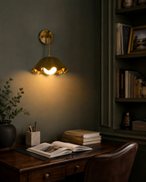 Marlow Modern Pleated Flower Wall Sconce installed in a sophisticated home office, showcasing the pleated flower-inspired metal shade and warm ambient lighting above a wooden desk and bookshelf.