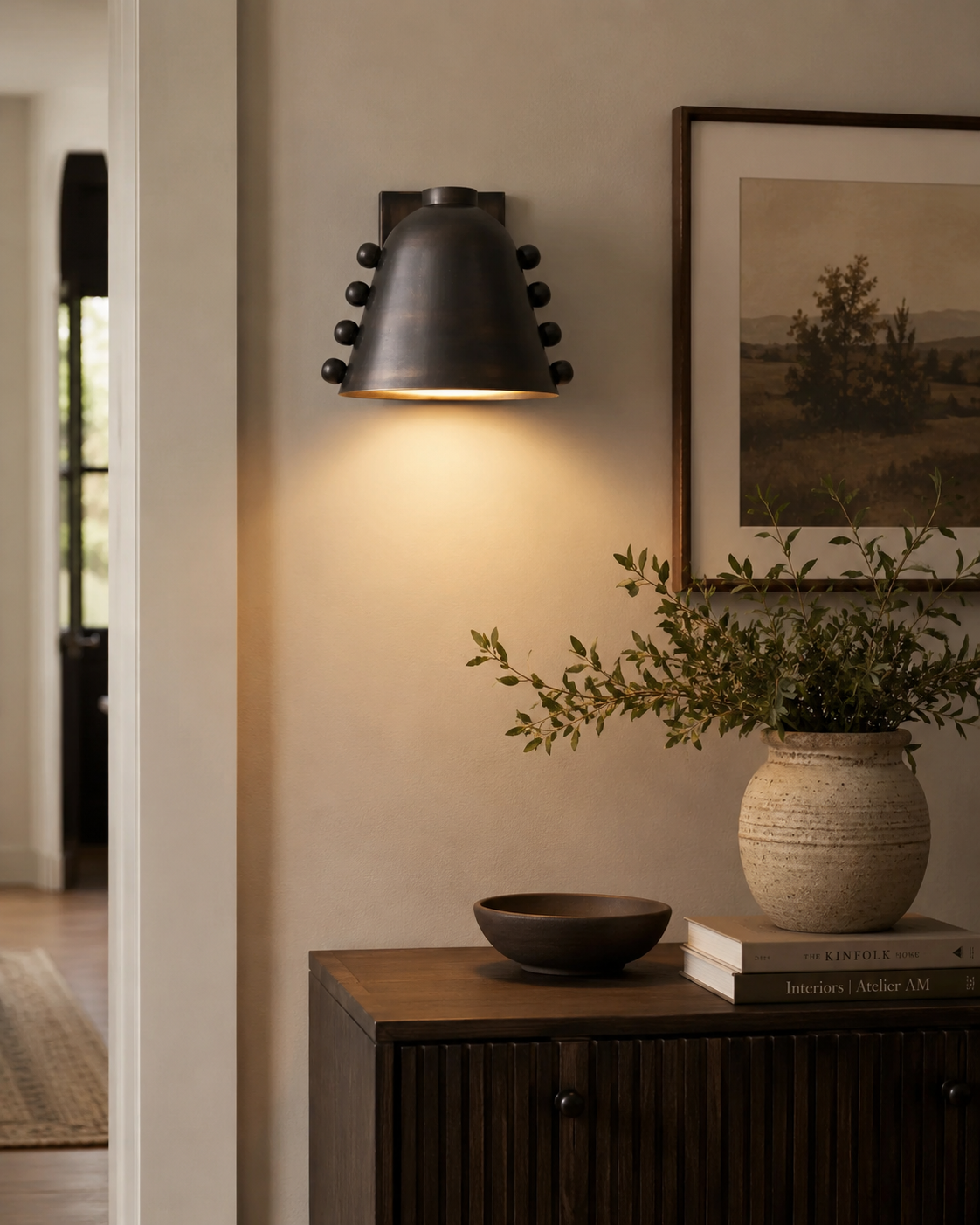 Marlow Riveted Dome Wall Sconce installed in a modern entryway, providing warm downward illumination with a handcrafted bronze dome shade.