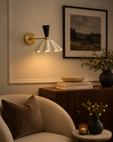 Marlow scalloped dome wall sconce with brass and black accents illuminated in a warm modern living room – Model 32826