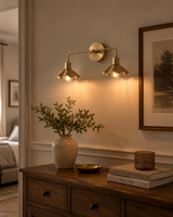 Marlow scalloped double wall sconce with two brass shades and warm exposed bulbs styled above a wooden console table.