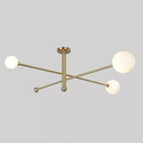 Front view of the Marrakech brass linear chandelier showcasing three spherical opal glass shades, crossed horizontal metal arms, and a central vertical ceiling stem.