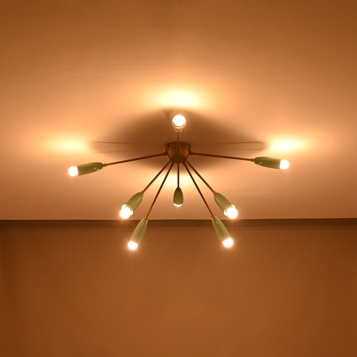 Modern mint and brass flush mount chandelier glowing warmly – room view