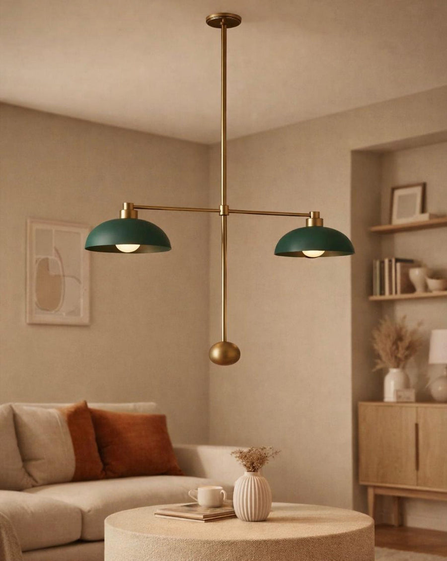 Mid-century inspired brass pendant light with dual green dome shades hanging above a modern living room coffee table.