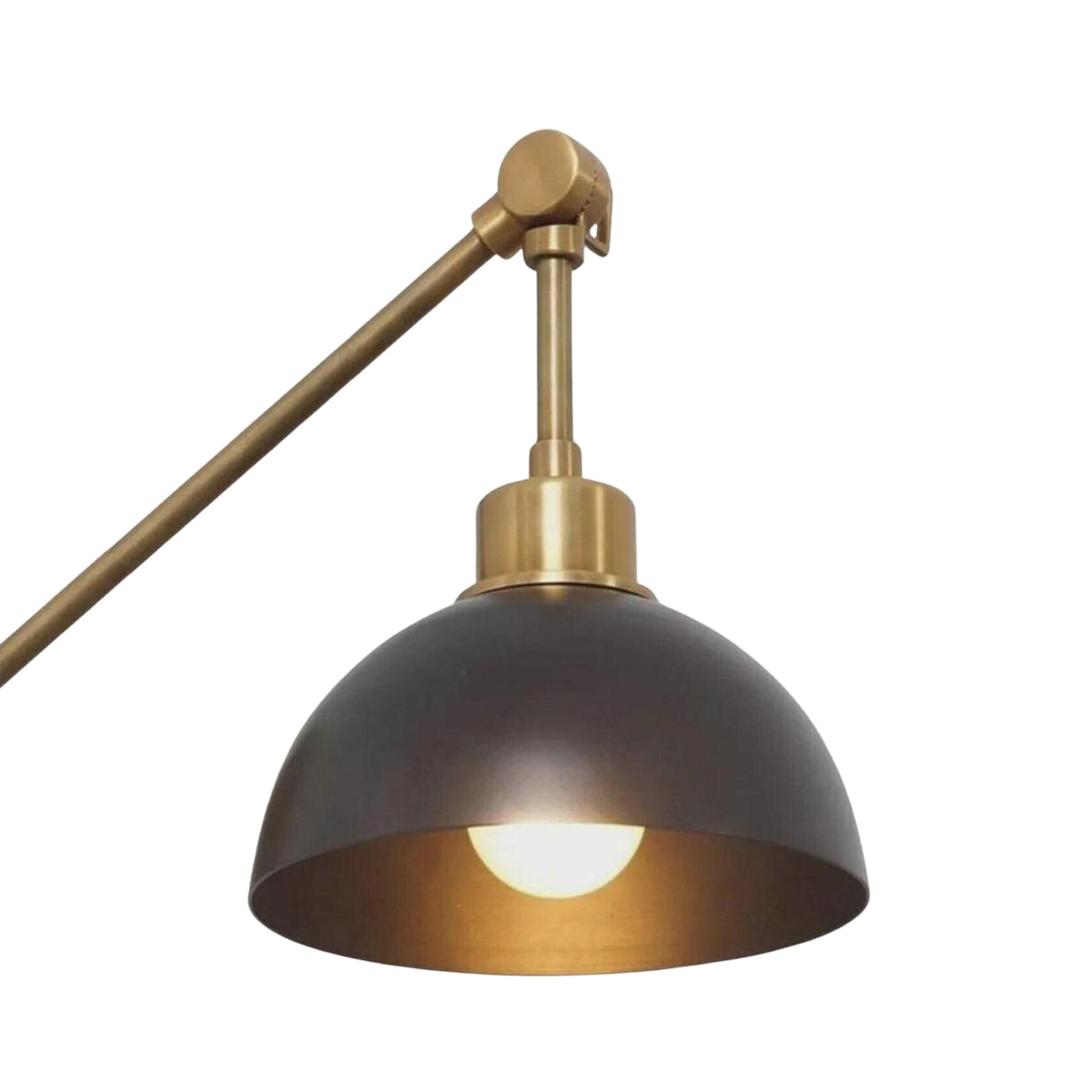 Milan adjustable wall sconce with illuminated dark dome shade and warm brass detailing, close-up view