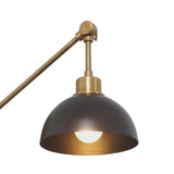 Milan adjustable wall sconce with illuminated dark dome shade and warm brass detailing, close-up view