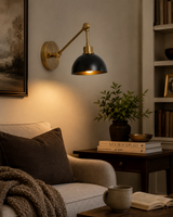 Milan adjustable brass dome wall sconce installed beside an armchair in a warm modern living room