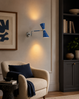 Milan adjustable blue double cone wall sconce with swing arm displayed in a modern living room reading corner.