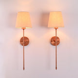 : Front view of Milan beige shade copper rod wall sconces shown as a matching pair with warm ambient glow
