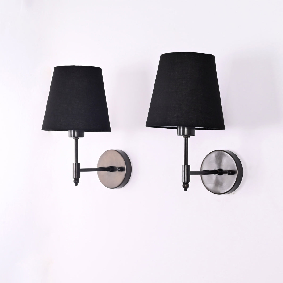 Angled view of Milan black wall sconces showing tapered fabric shades and compact wall projection.