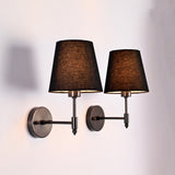 Close angled view of Milan black fabric shade wall sconces with round backplates and short stems.