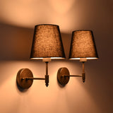 Dark room view of Milan black shade wall sconces creating warm dramatic light on the wall.