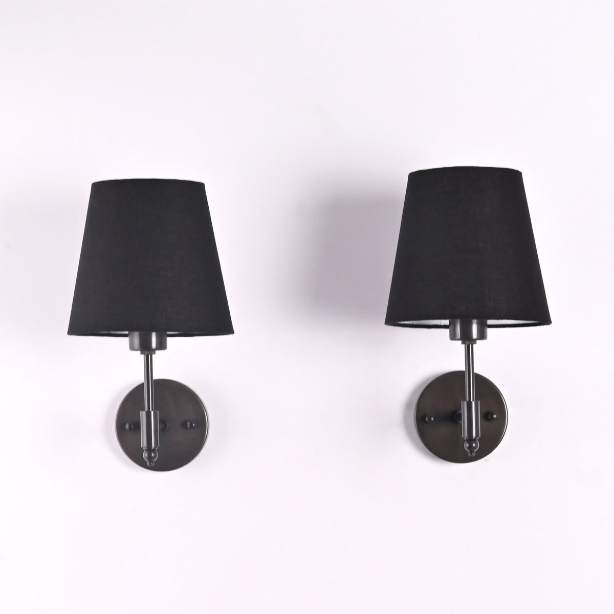 Front view of Milan black shade wall sconces with short stem design and round backplates.