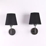 Front view of Milan black shade wall sconces with short stem design and round backplates.