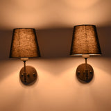 Illuminated Milan black shade wall sconces casting soft warm light upward and downward on the wall.