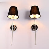 Low angle view of black shade chrome wall sconces showing warm light from beneath the shades.