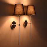 Warm angle view of black shade chrome rod wall sconces creating soft ambient wall illumination.