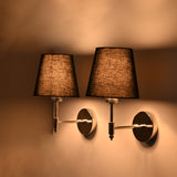 : Angled illuminated view of Milan polished chrome wall sconce with black fabric shade creating warm accent lighting for modern interiors.