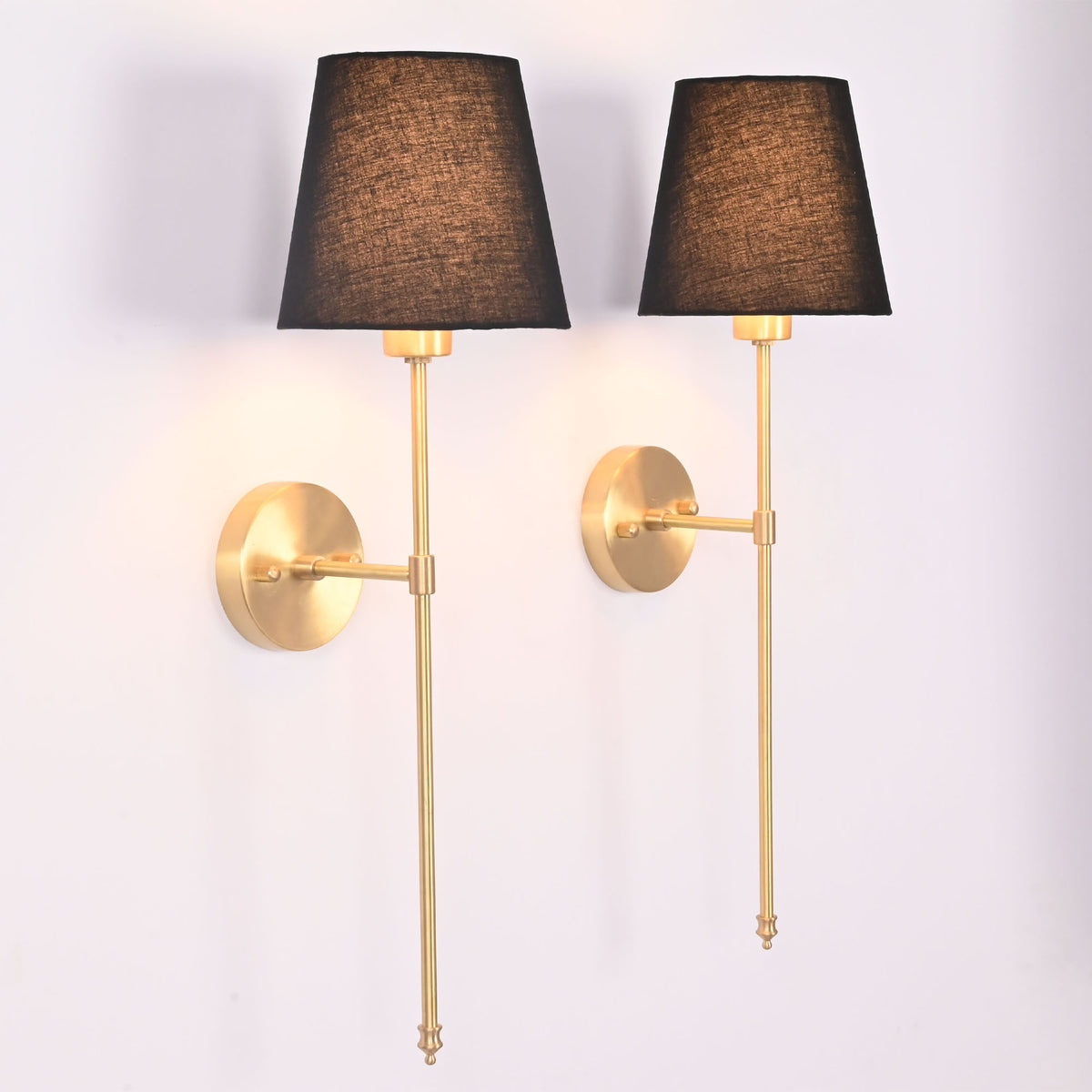 Angled view of Milan black shade rod wall sconces with slim stems and classic round wall plates.