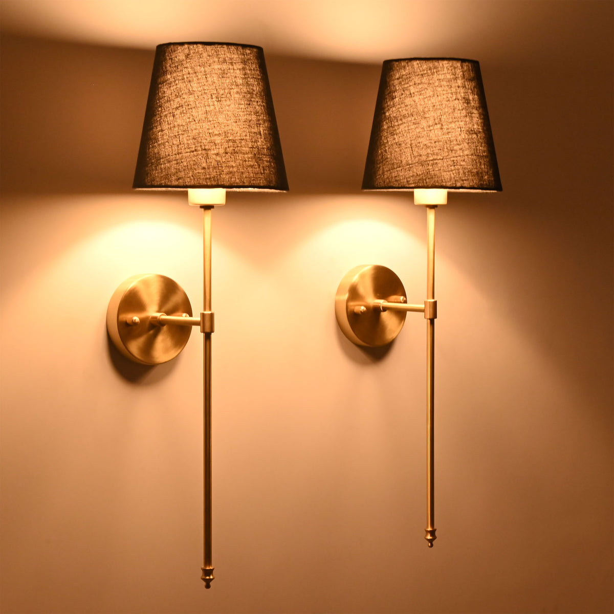 Pair of illuminated black shade wall sconces creating warm ambient glow with refined classic styling.