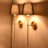 Milan black shade wall sconces glowing warmly with textured fabric shades and soft wall illumination.