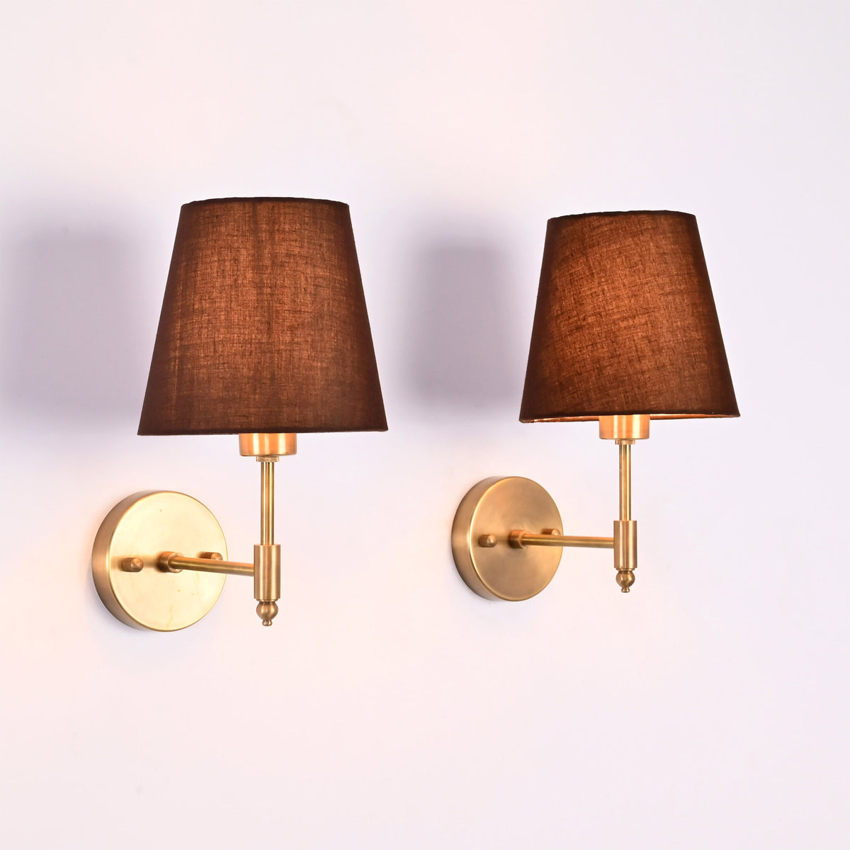 Illuminated Milan Brown Shade Antique Brass Short Wall Sconce emitting a warm ambient glow through the brown fabric shade.