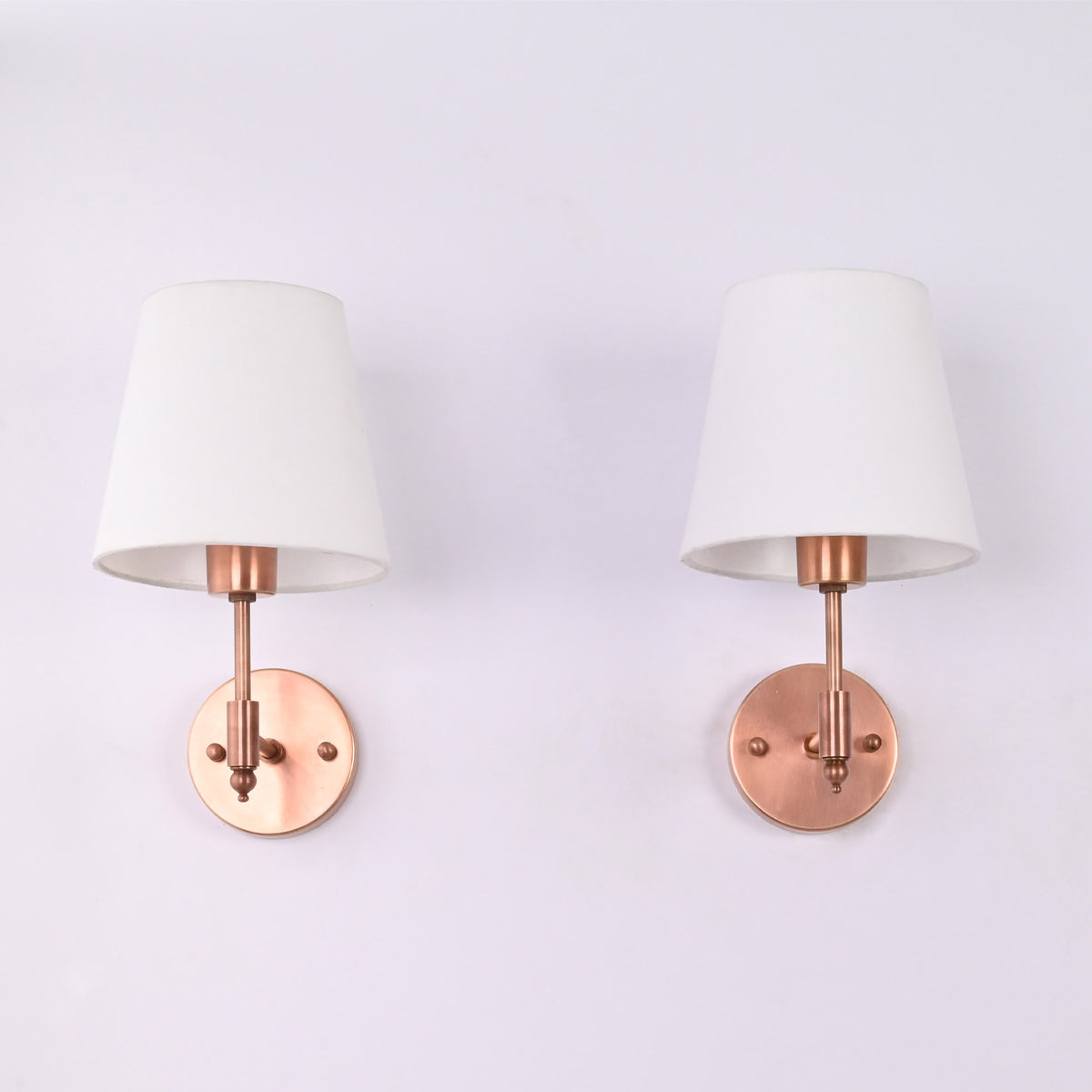 Angled front view of the Milan copper antique brass wall sconce with a white tapered fabric shade, showcasing its elegant handcrafted design and compact wall-mounted profile.