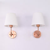 Angled front view of the Milan copper antique brass wall sconce with a white tapered fabric shade, showcasing its elegant handcrafted design and compact wall-mounted profile.