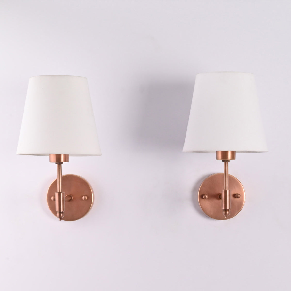 Front view of the Milan copper antique solid brass wall sconce with a white tapered fabric shade, featuring a handcrafted modern wall light for bedrooms, hallways, living rooms, and luxury interiors.