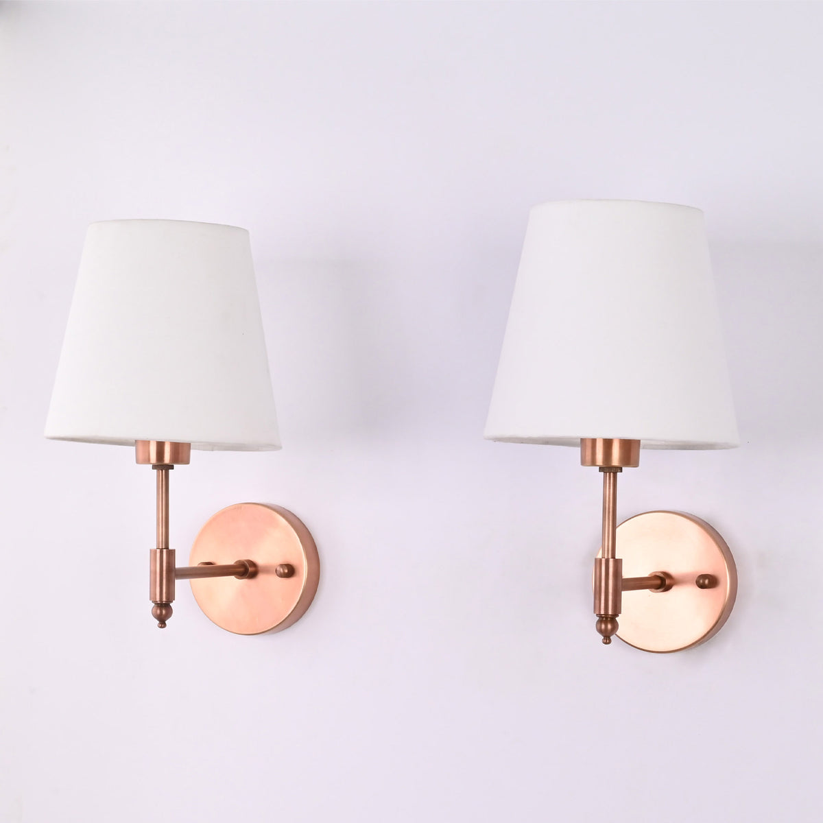 Pair of Milan copper antique wall sconces with white tapered fabric shades mounted on a wall, ideal for bedside lighting, hallways, bathrooms, and modern transitional interiors.
