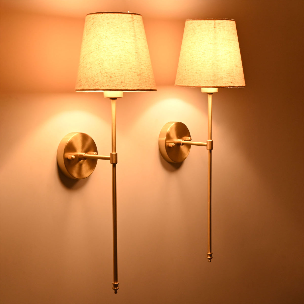 Pair of illuminated cream shade wall sconces creating soft warm glow for classic interiors.