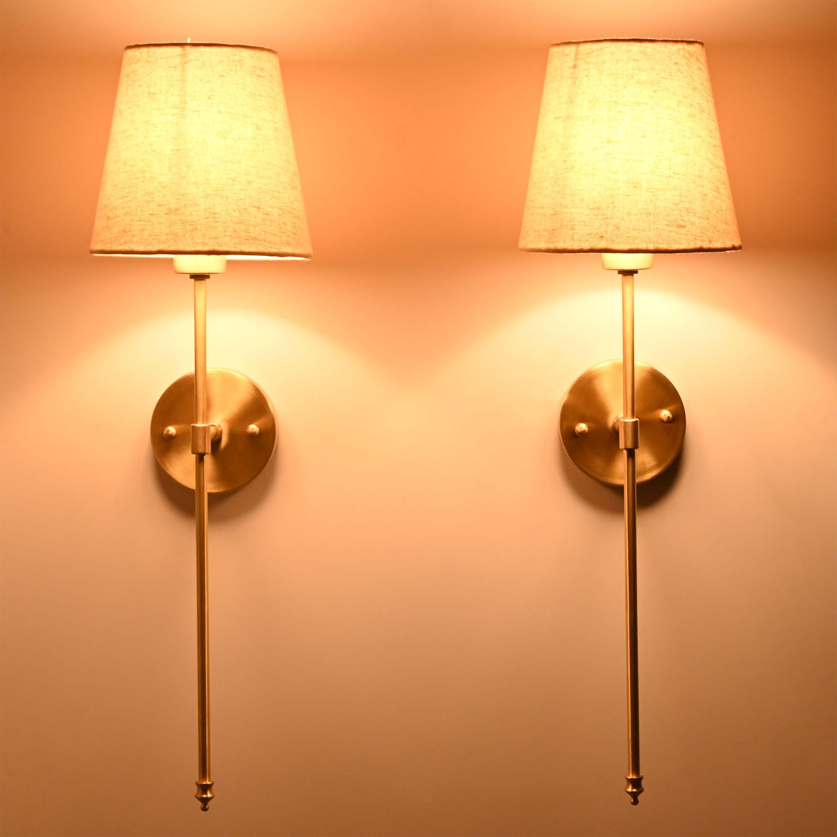 Milan cream shade wall sconces glowing warmly with soft diffused light and elegant wall presence.