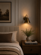 Milan curved arm cone wall sconce installed beside a bed providing warm downward ambient lighting, Model 32791