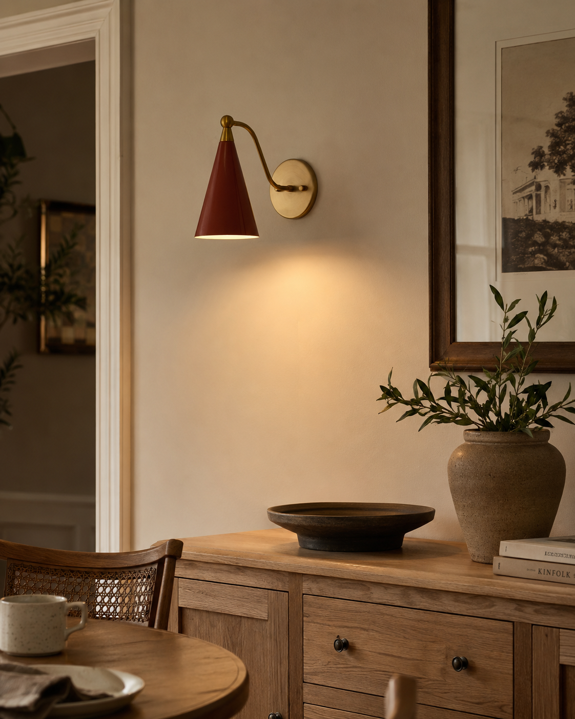 Milan Curved Arm Cone Wall Sconce installed in a warm contemporary dining room, casting soft ambient lighting above a wooden sideboard with modern Scandinavian décor.