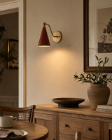 Milan Curved Arm Cone Wall Sconce installed in a warm contemporary dining room, casting soft ambient lighting above a wooden sideboard with modern Scandinavian décor.
