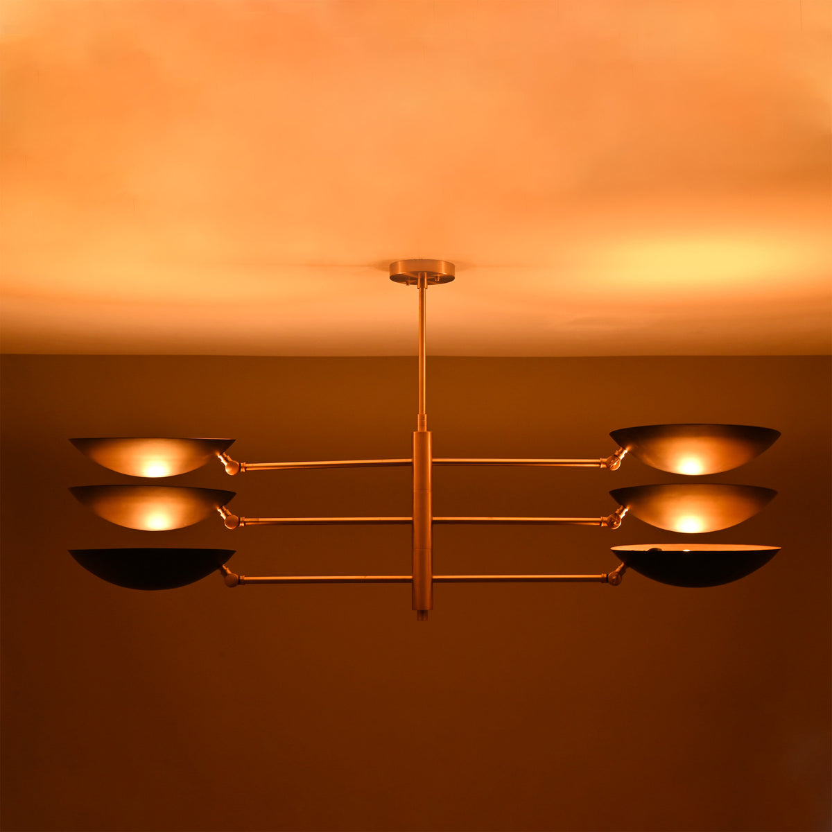 Milan Disc Linear Chandelier installed on ceiling with six black disc shades and warm upward glow.