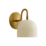 Front angled view of the Milan Dome Wall Sconce showcasing a handcrafted white dome shade, curved solid brass arm, and circular wall canopy.