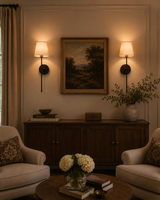 Milan ivory shade black wall sconces installed beside framed artwork in a warm classic living room.